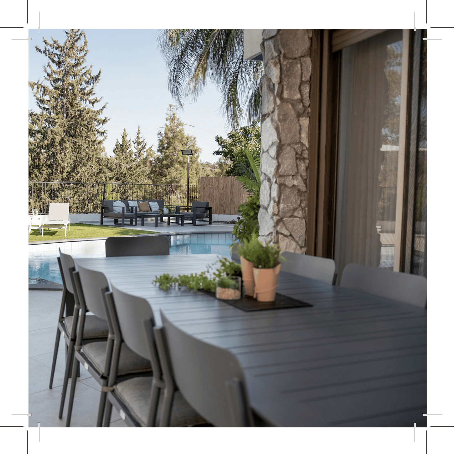 Outdoor dining area with table, chairs, pool, and greenery