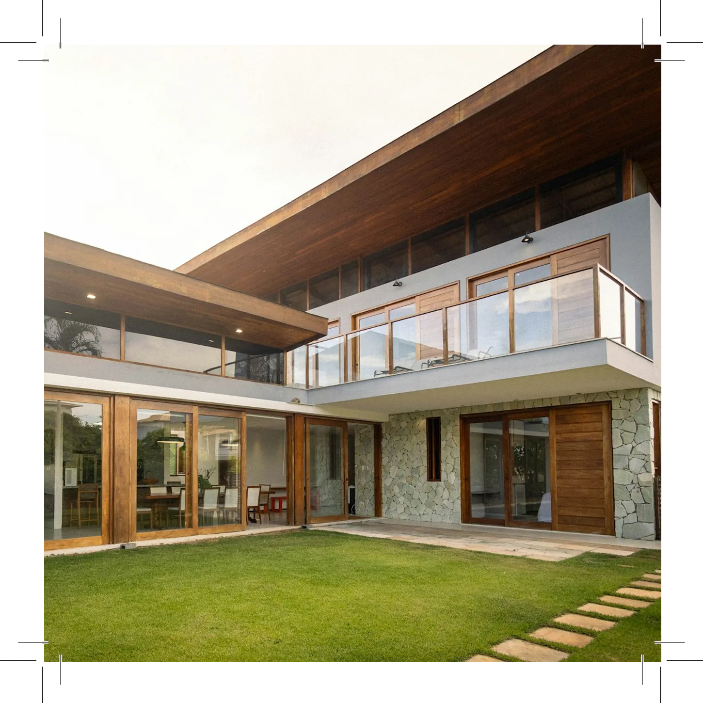 Modern house California real estate with glass windows, stone walls, and green lawn