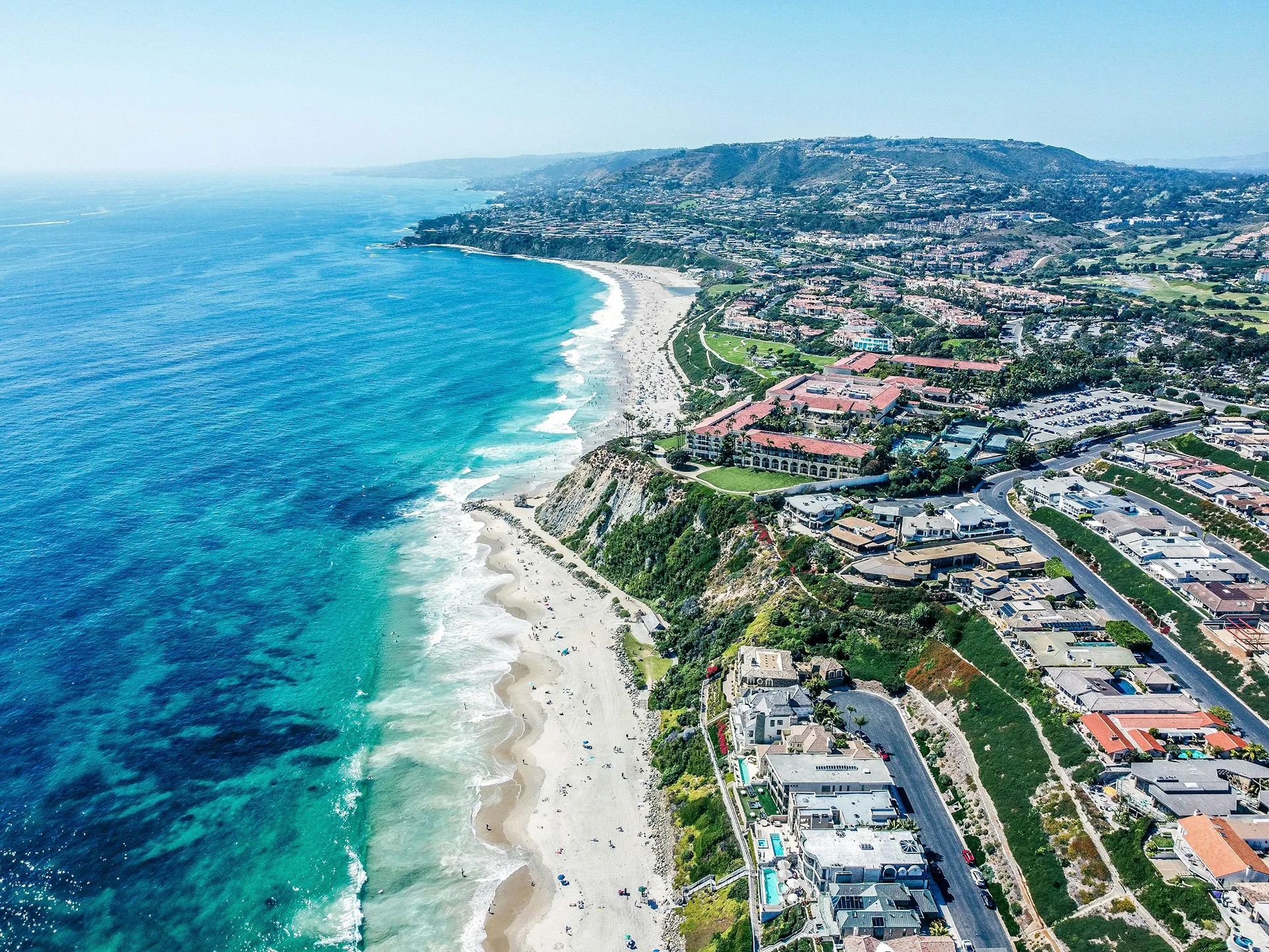 Coastal area with beach, ocean, and houses on hill