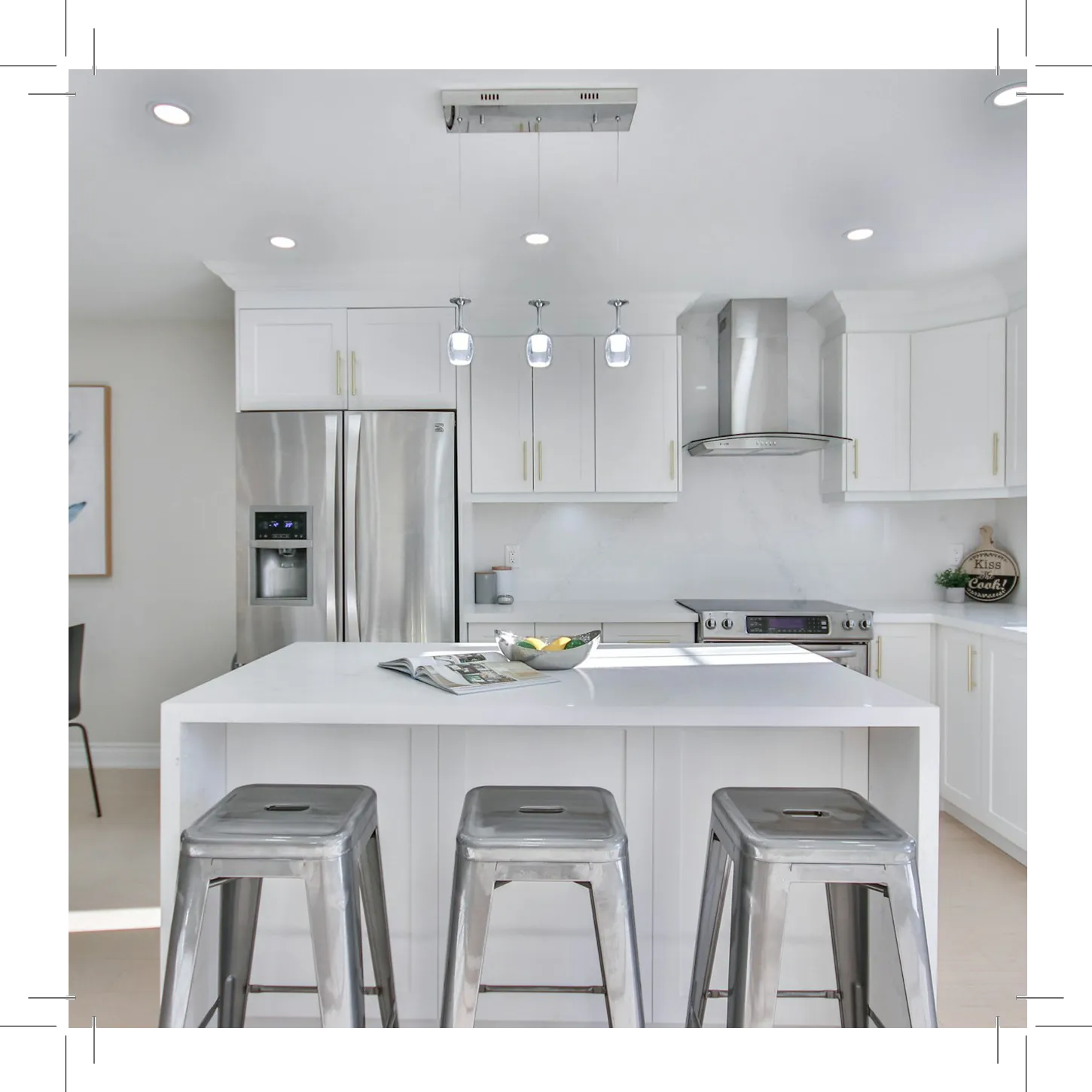 Kitchen with white cabinets, appliances, and bar stools