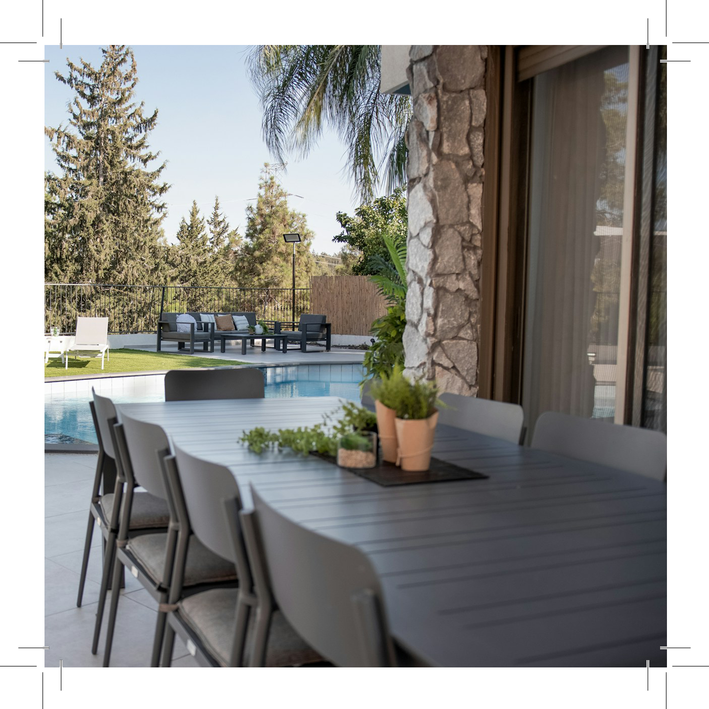 Outdoor dining area with table, chairs, pool, and greenery